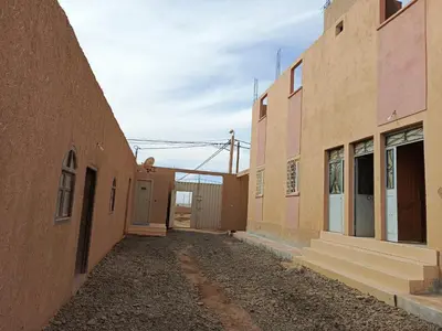 an empty alley between two buildings with a fence at taddart in Merzouga