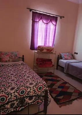 a bedroom with a bed and a window with pink curtains at taddart in Merzouga
