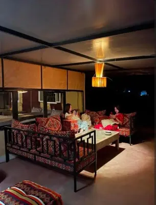 two people sitting on a couch in a living room at Luxury camp in Merzouga