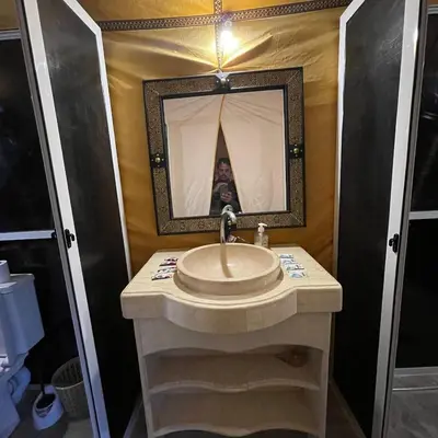 a bathroom with a sink and a person in the mirror at Luxury camp in Merzouga