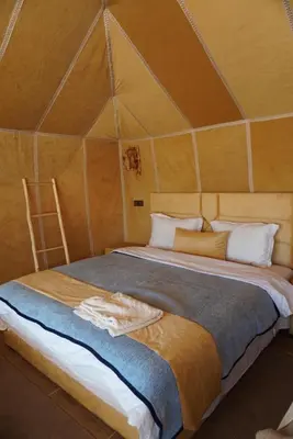 a large bed in a room with a triangular ceiling at Ousaadi luxury desert camp in Merzouga