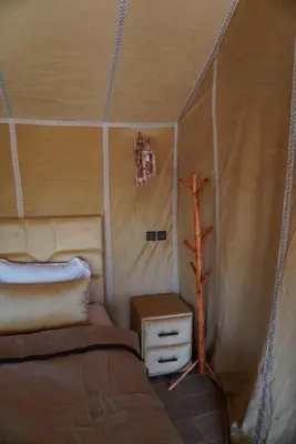 a bedroom with a bed and a tree in a tent at Ousaadi luxury desert camp in Merzouga