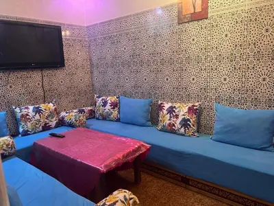 a blue couch with pillows and a tv on a wall at Charmante Maison et Comfortable à Ifrane in Ifrane