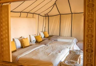 a room with three beds in a tent at Celestial Dunes Camp in Merzouga