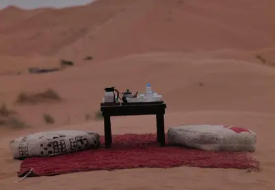 a table in the middle of a desert with two pillows at Celestial Dunes Camp in Merzouga