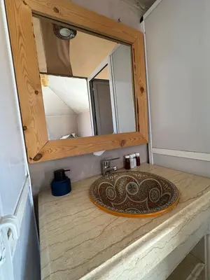 a bathroom with a sink and a mirror on a counter at Celestial Dunes Camp in Merzouga