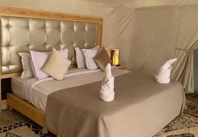 a bedroom with a large bed with white pillows at Celestial Dunes Camp in Merzouga