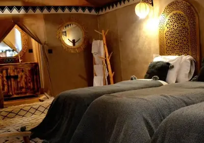a bedroom with two beds and a clock on the wall at Merzouga Atlantis in Merzouga