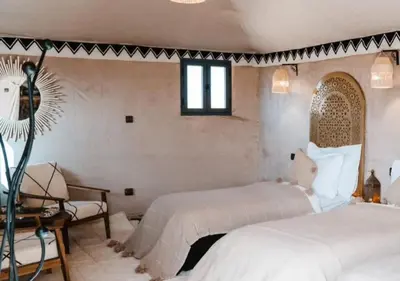 a bedroom with two beds and a chair at Merzouga Atlantis in Merzouga