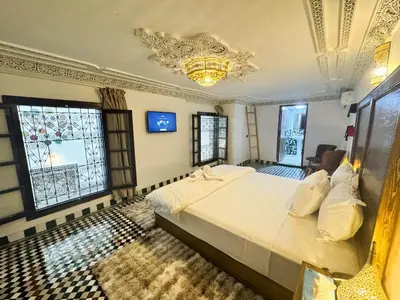a bedroom with a bed and a chandelier and windows at Riad Azul Fes & SPA in Fès