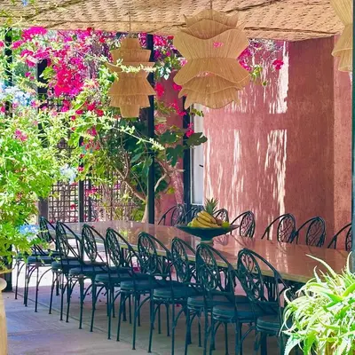 a long wooden table with chairs and flowers at Villa Ishtar in Marrakech