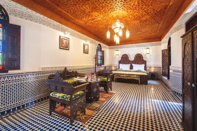 a room with a bedroom with a bed and a table at Riad Fes Maya suite & spa in Fès