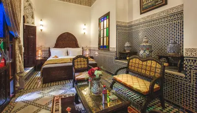 a bedroom with a bed and a table and chairs at Riad Fes Maya suite & spa in Fès