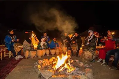 a group of people sitting around a large fire at Camping Activities Merzouga in Merzouga