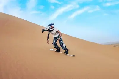 a man riding a snowboard down a sand dune at Camping Activities Merzouga in Merzouga