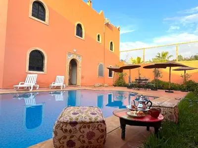 a house with a swimming pool with a table and chairs at Palais Aya in Oulad Akkou