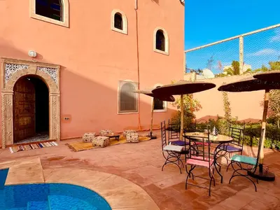 a patio with a table and chairs and an umbrella at Palais Aya in Oulad Akkou