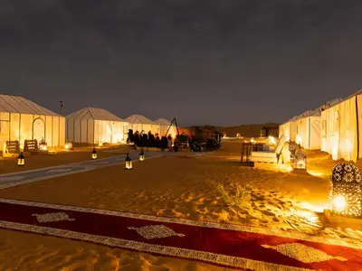 a group of people sitting outside of domes at night at Arsura Luxury Camp in Merzouga
