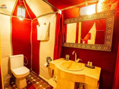 a bathroom with a sink and a toilet and a mirror at Arsura Luxury Camp in Merzouga