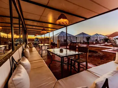 a restaurant with tables and chairs and tents at Arsura Luxury Camp in Merzouga