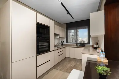 a kitchen with white cabinets and a large window at Modern Loft in City Center in Oulad Akkou