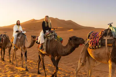 a group of people riding on camels in the desert at Merzouga Standard Camp in Merzouga