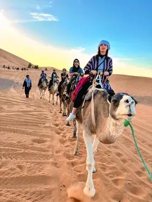a group of people riding on a camel in the desert at Merzouga Standard Camp in Merzouga