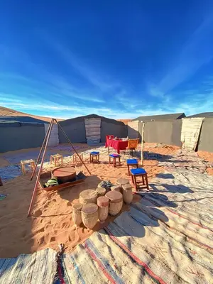 a tent with chairs and a table in the desert at Merzouga Standard Camp in Merzouga