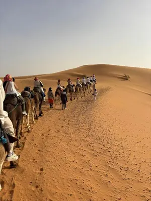 a group of people riding on camels in the desert at Royal Erg Chebbi Luxury Camp in Hassilabied