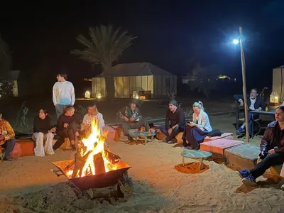 a group of people sitting around a fire at Aziz luxury camp in Merzouga