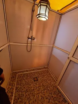 a shower with a light and a tiled floor at Aziz luxury camp in Merzouga