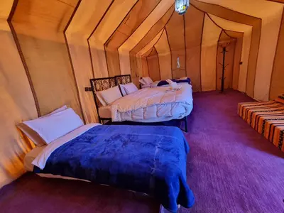 a room with two beds in a tent at Aziz luxury camp in Merzouga