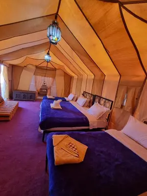 a room with three beds in a tent at Aziz luxury camp in Merzouga