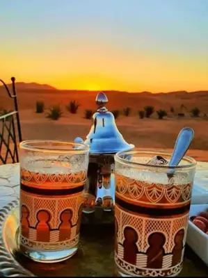 two glasses of tea on a table with a view of the desert at Family Dunes Camp in Merzouga