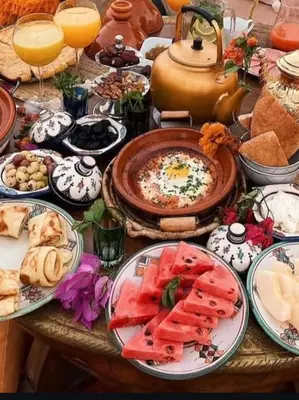 a table filled with plates of food and drinks at Family Dunes Camp in Merzouga