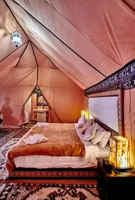 a bedroom with a bed in a tent at Merzouga palace camp in Merzouga