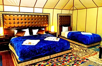 a bedroom with two beds in a tent at Merzouga palace camp in Merzouga
