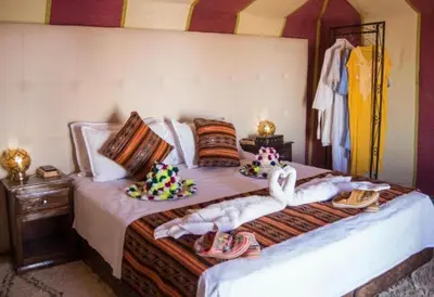 a bedroom with two swans sitting on a bed at Merzouga palace camp in Merzouga
