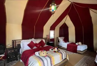 two beds in a room with red and white walls at Merzouga palace camp in Merzouga