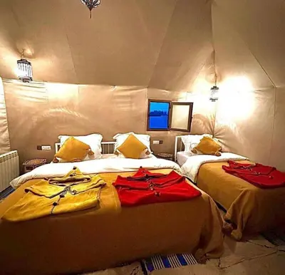 two beds in a room with red clothes on them at Merzouga palace camp in Merzouga