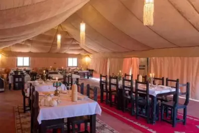 a dining room with tables and chairs in a tent at Merzouga palace camp in Merzouga