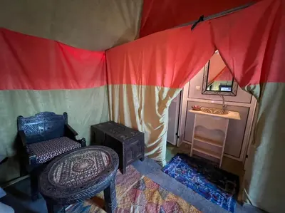 a room with a bed and a chair in a tent at Luxury camp desert in Merzouga
