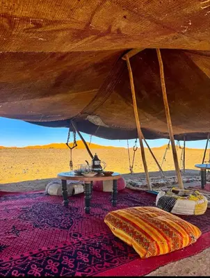 a large tent with a table in the desert at Luxury camp desert in Merzouga