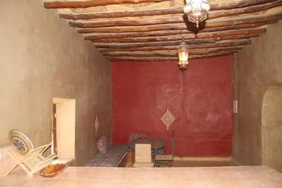 a room with a red wall and a wooden ceiling at dorada apartamento in Merzouga