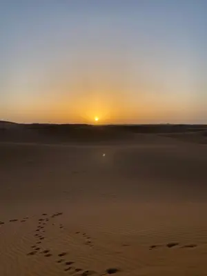 a sunset on the beach with footprints in the sand at Colorado Desert Camp in El Gouera