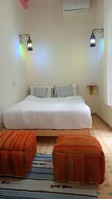a bedroom with a large bed with two ottomans at chez dar Ayoub in Fès