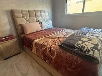 a bedroom with a large bed with a wooden night stand at Darappart in Fès