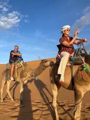 a man and a woman riding on a camel in the desert at Desert Family Camp in El Gouera