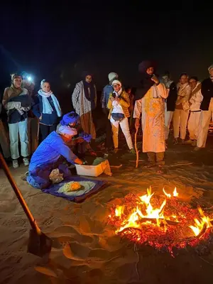 a group of people standing around a fire at Desert Family Camp in El Gouera