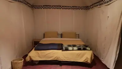 a bedroom with a bed in a room with two chairs at Desert Family Camp in El Gouera